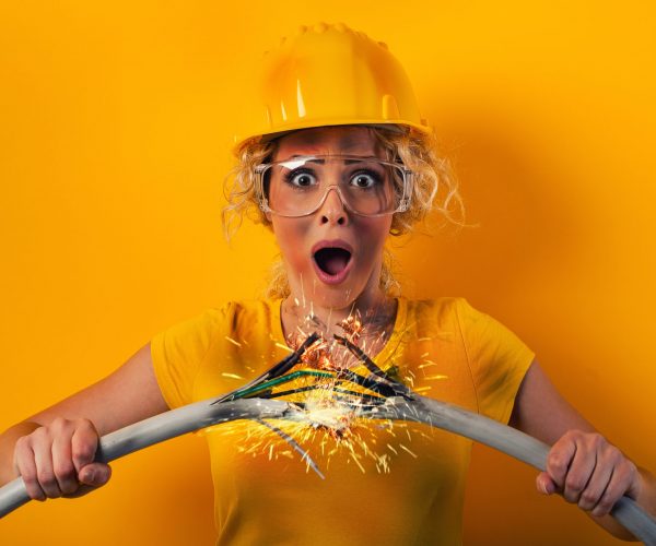 Worker girl with hat breaks an electric cable.